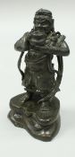 A late 17th or early 18th Century Chinese bronze figure of an Immortal holding an urn aloft in his
