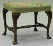 A 19th Century walnut framed stool with needlework upholstered seat on cabriole legs with acanthus