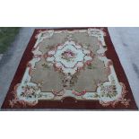 An Aubusson carpet, the central floral medallion on a beige ground within a burgundy border,