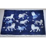 A Chinese woollen rug, the central panel decorated with lions on a dark blue ground,