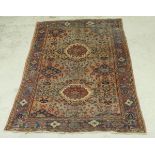 A Persian carpet with two floral medallions on a pale red ground, with all over floral decoration,