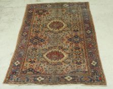 A Persian carpet with two floral medallions on a pale red ground, with all over floral decoration,