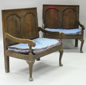 A pair of 18th Century oak two seat settles, the backs with shaped fielded panels,