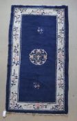 A Chinese rug, the central panel set with three floral sprays on a dark blue ground,