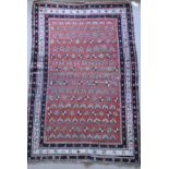 A Caucasian rug, the central panel set with repeating motifs on a red ground,