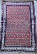 A Caucasian rug, the central panel set with repeating motifs on a red ground,