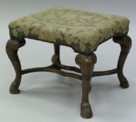 A walnut framed stool in the 18th Century Continental manner with foliate needlework upholstered