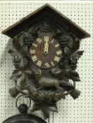 An early 20th Century carved wooden cased cuckoo clock decorated with grape and vine and running