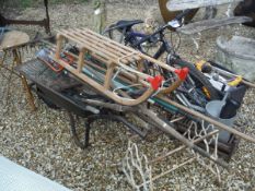 A collection of various garden tools, wheelbarrow, hayrack,