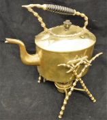 A brass spirit kettle on stand with turned wooden handle on a bobbin decorated X frame to base with