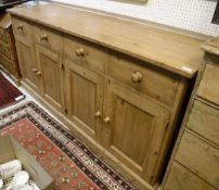 A modern pine dresser, the plain top above four drawers and four cupboard doors,