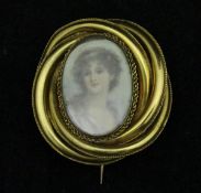 A gold coloured brooch with miniature portrait study of a young woman with band in her hair,