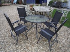 A glass topped garden table and four folding chairs