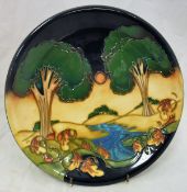 A Moorcroft Pottery plate depicting a river landscape at sunset,