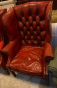 A pair of early 20th Century wing back armchairs in the Georgian taste with red leather button back