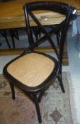 A set of six black painted dining chairs with cane seats in the manner of Oka