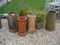 A collection of four various terracotta chimney pots together with seven various garden planters