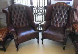 A pair of Georgian style brown leatherette wing back armchairs with cabriole front legs