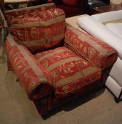 A modern upholstered scroll armchair with Egyptian style decorated upholstery raised on turned legs