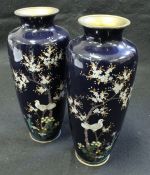 A pair of Japanese cloisonné vases decorated with birds amongst blossoming foliage on a deep blue