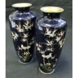 A pair of Japanese cloisonné vases decorated with birds amongst blossoming foliage on a deep blue