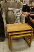 A wicker framed wing back armchair, nest of three tables,