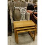 A wicker framed wing back armchair, nest of three tables,