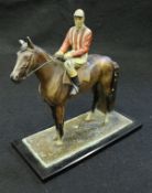 A circa 1900 cold-painted cast metal table lighter / match striker as a mounted jockey in red and