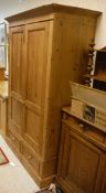A pine two door wardrobe with two drawers on a plinth base
