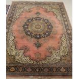 A Persian rug, the central panel set with floral decorated medallion on a salmon pink ground,