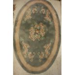 A Chinese superwash rug of oval form, the central panel set with dragons on a sage ground,