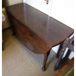 A George III mahogany oval drop-leaf dining table on turned tapering legs to heavy pad feet