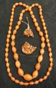 An amber bead necklace and amber pendant of bird and berries