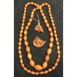 An amber bead necklace and amber pendant of bird and berries