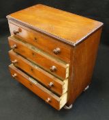 A Victorian mahogany miniature chest of four long drawers on turned feet
