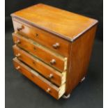 A Victorian mahogany miniature chest of four long drawers on turned feet