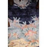A Chinese silk rug, the central panel set with floral decorated medallion on a blue ground,