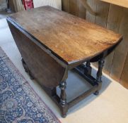 An 18th Century oak gate-leg table on baluster turned supports and a stretchered base