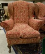 Two pink ground and patterned wing back armchairs raised upon mahogany cabriole front legs