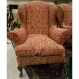 Two pink ground and patterned wing back armchairs raised upon mahogany cabriole front legs