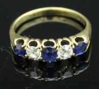 A yellow metal dress ring set with three sapphires and two diamonds, each approx 0.
