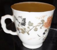A Chinese export porcelain cup decorated with flowers on a white ground,
