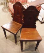 A pair of Victorian mahogany hall chairs with fan carved backs over plain panel seats on turned and