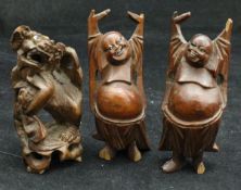 Three carved cherry root figures including a Dog of Fo and two Buddhas with their hands held aloft