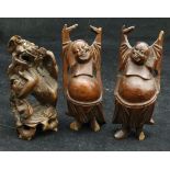 Three carved cherry root figures including a Dog of Fo and two Buddhas with their hands held aloft