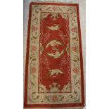 A Chinese silk rug, the central panel set with cranes on a red ground,