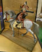 A model of a Japanese Samurai Warrior on horseback housed in a four-sided glass case,