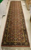 An Oriental runner, the central panel set with all over floral decoration on a red ground,