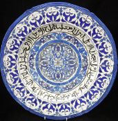 A Kutayha (Turkey) charger with white ground and blue patterned decoration and black script,