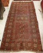 A Bokhara rug, the central panel set with geometric designs on a dark red ground,